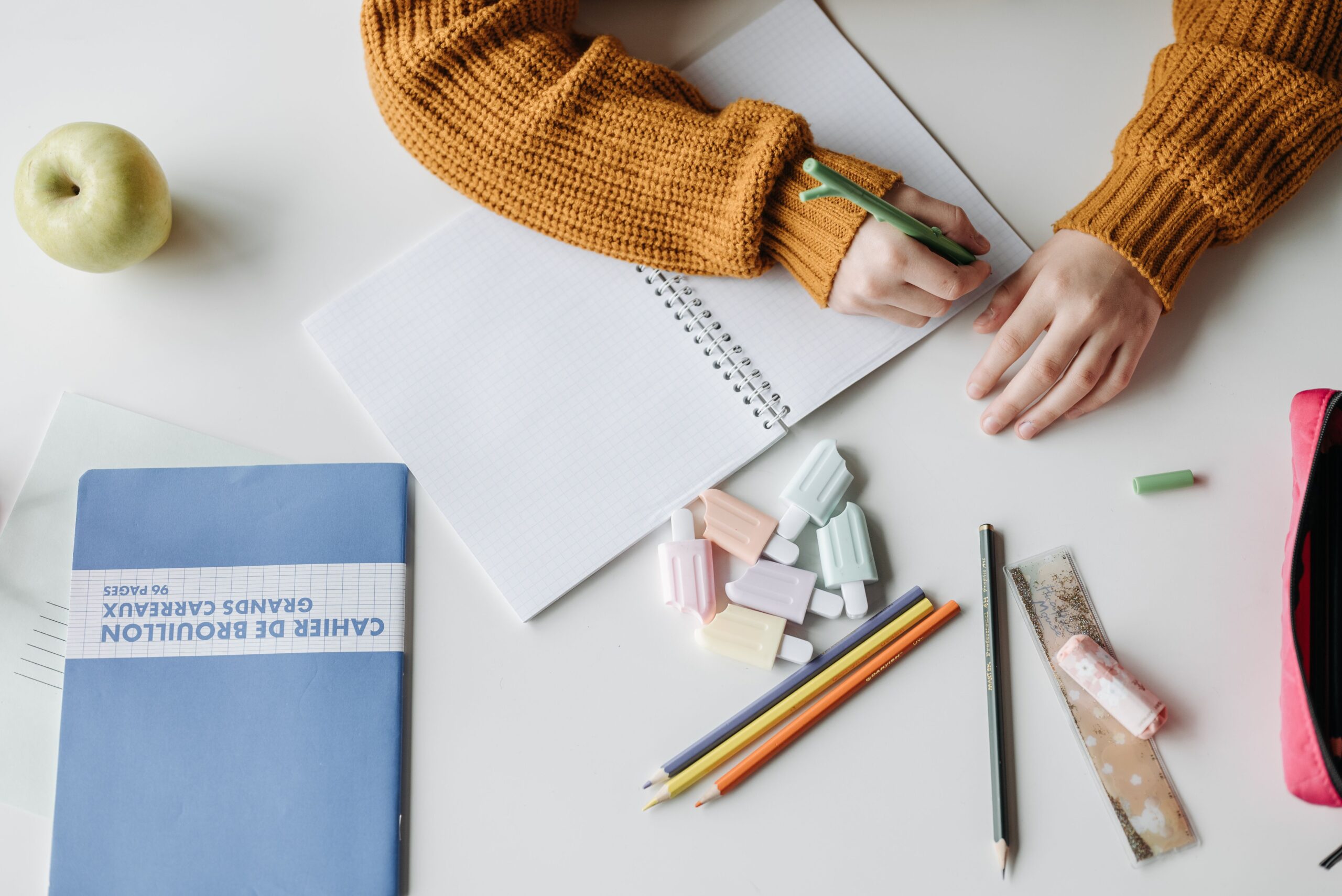 A student revises writing in a notebook, where erasing depends on lifting graphite from paper fibers.