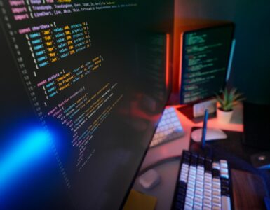 Programming code displayed on screens, representing error-correcting codes that help digital messages survive noise.