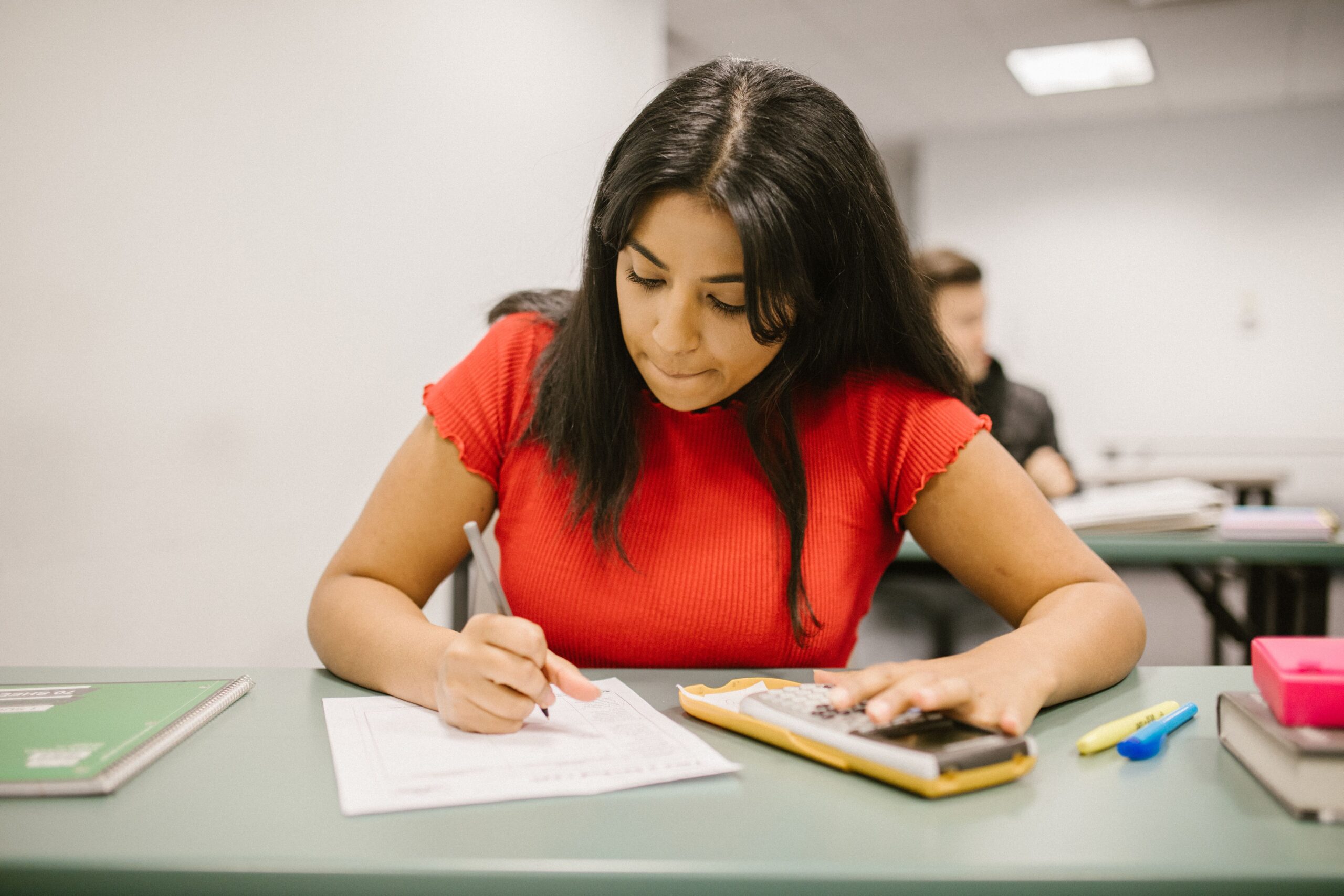 A calculator beside course notes used to compare homework, quiz, test, and exam weights.