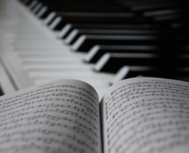 Piano keys beside open sheet music for studying repeating ostinato patterns in music.