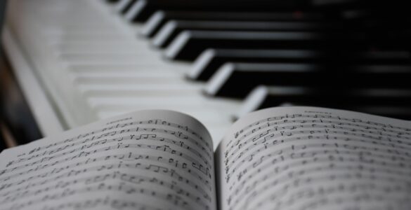 Piano keys beside open sheet music for studying repeating ostinato patterns in music.