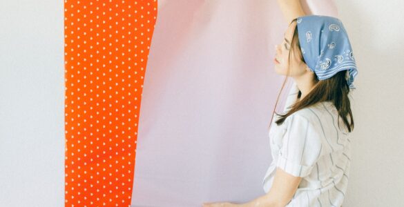 A person applying removable wallpaper to a painted wall, showing the backing peeled away from the adhesive sheet.