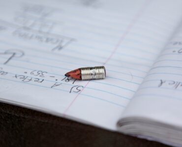A pencil rests on notebook paper, showing the everyday writing surface where graphite leaves marks.