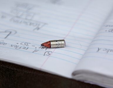 A pencil rests on notebook paper, showing the everyday writing surface where graphite leaves marks.