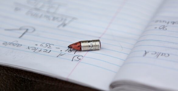 A pencil rests on notebook paper, showing the everyday writing surface where graphite leaves marks.