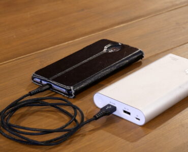 A smartphone charging from a portable power bank, representing how rechargeable batteries lose capacity over time.
