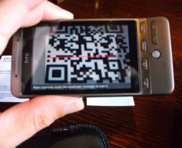 A phone camera scanning a printed QR code, representing how phones turn square patterns into digital information.