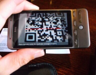 A phone camera scanning a printed QR code, representing how phones turn square patterns into digital information.
