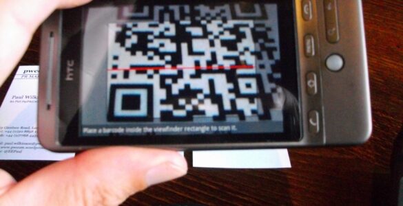 A phone camera scanning a printed QR code, representing how phones turn square patterns into digital information.