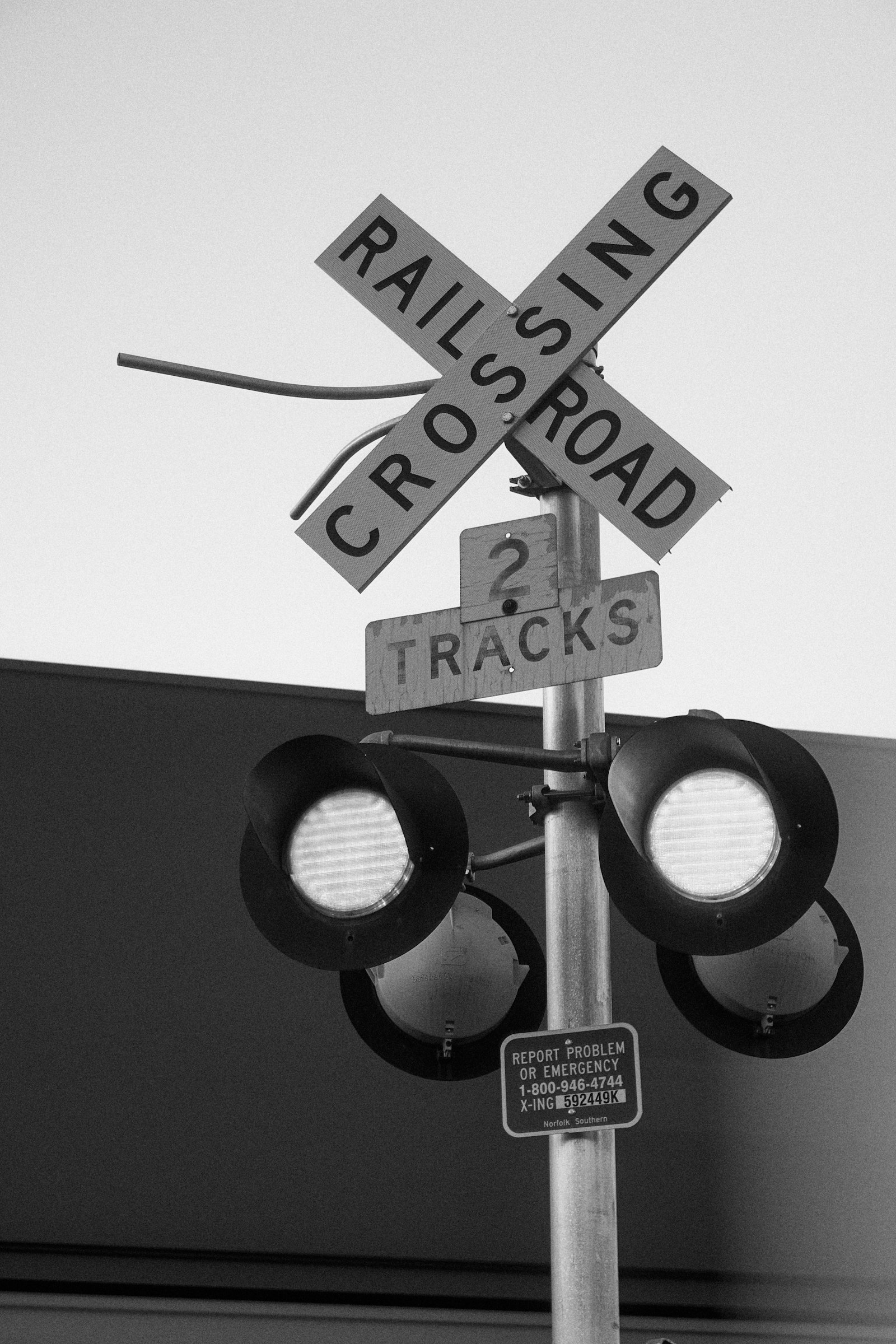 A railroad crossing sign with warning lights, showing the kind of signal school bus drivers check before crossing tracks.