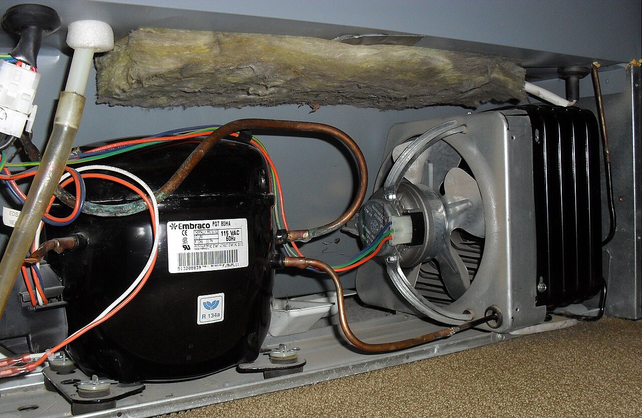 The compressor and condenser coils on the back of a refrigerator where heat leaves the appliance