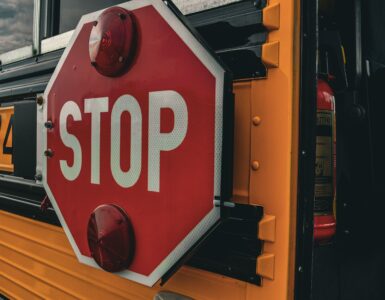 Close-up of a red stop sign extended from the side of a yellow school bus.