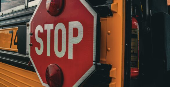 Close-up of a red stop sign extended from the side of a yellow school bus.