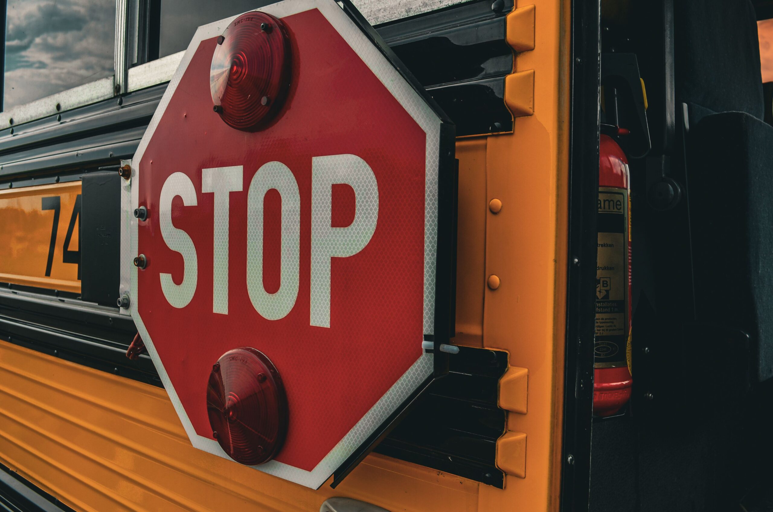 Close-up of a red stop sign extended from the side of a yellow school bus.