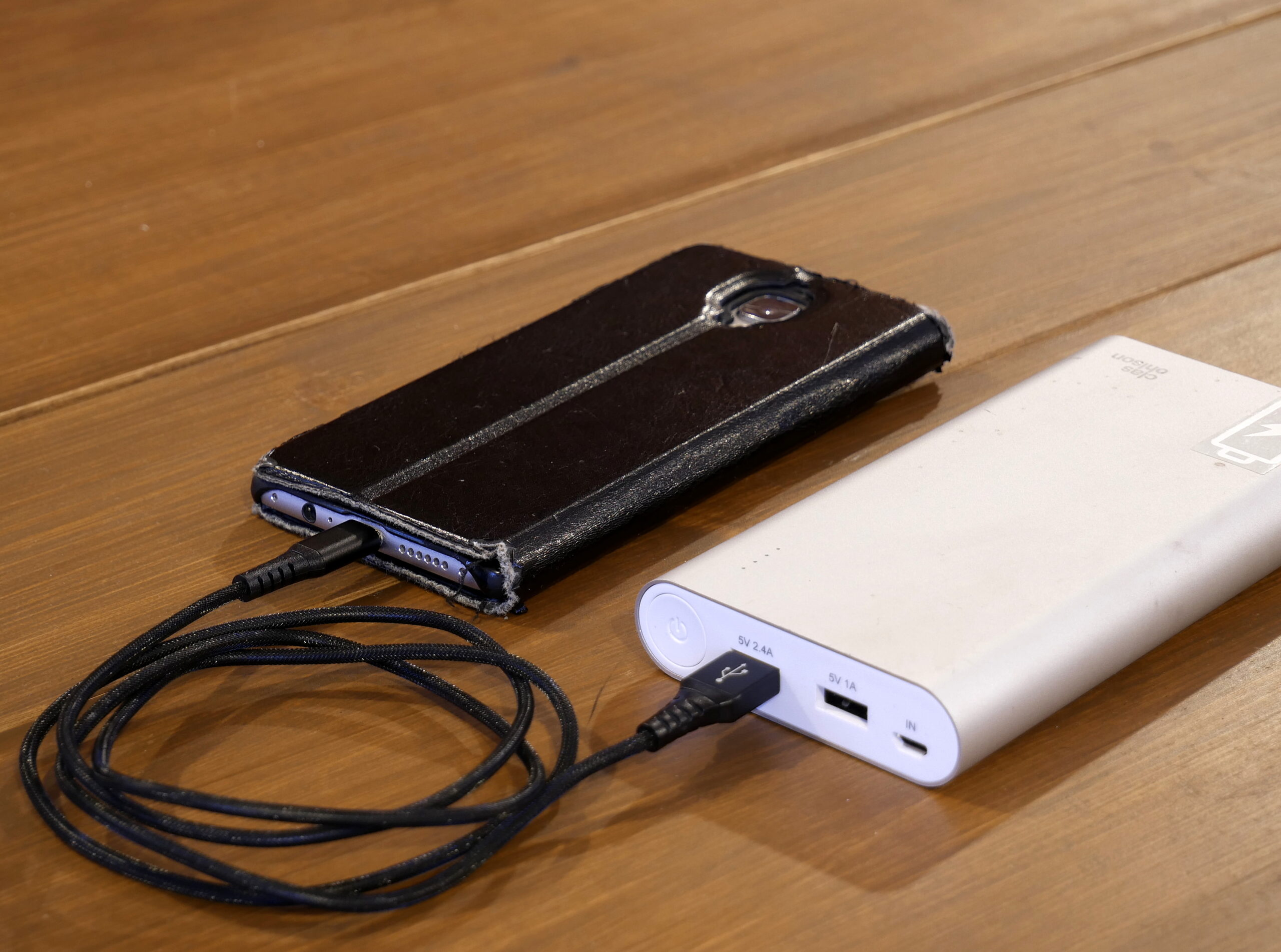 A smartphone charging from a portable power bank, representing partial charges and charge cycles.