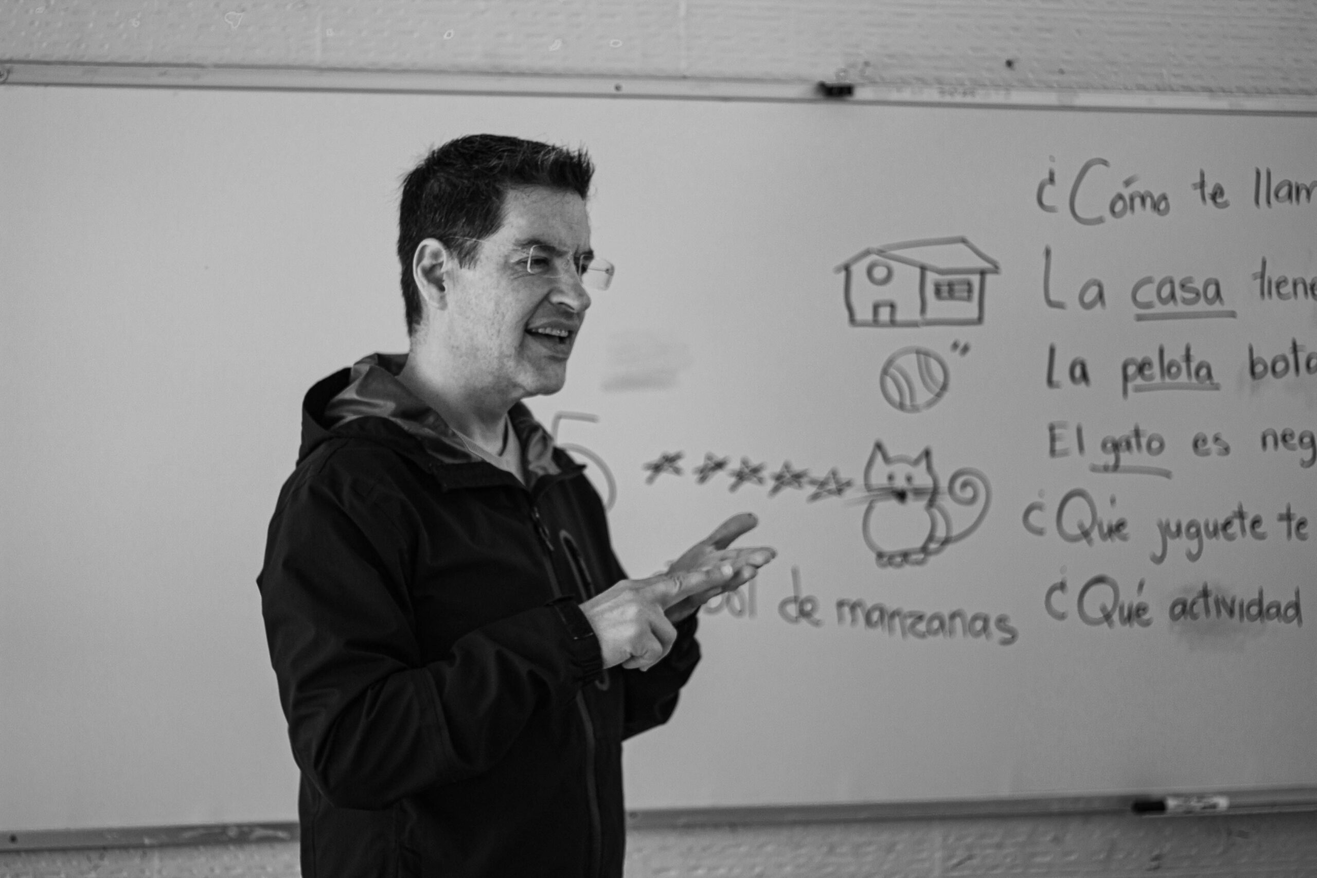Spanish teacher reviewing stem-changing verb examples on a classroom whiteboard