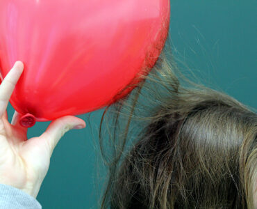 A charged balloon attracts strands of hair during a static electricity demonstration.