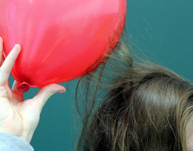 A charged balloon attracts strands of hair during a static electricity demonstration.