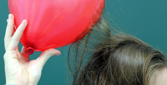 A charged balloon attracts strands of hair during a static electricity demonstration.