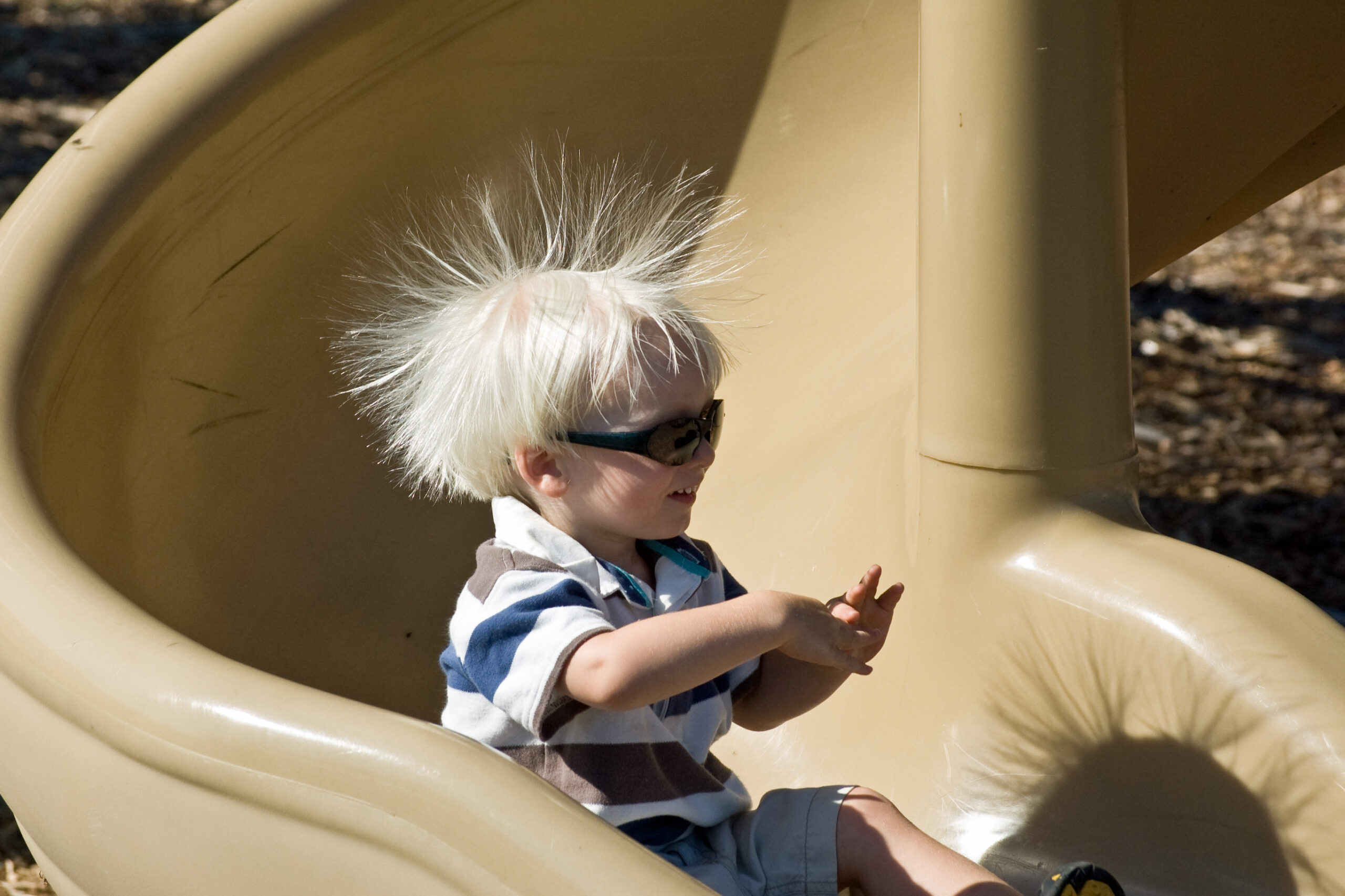 A child on a slide with hair lifted by static electricity after contact and friction.