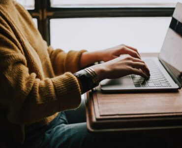 A student typing on a laptop while drafting a clear email to a teacher.