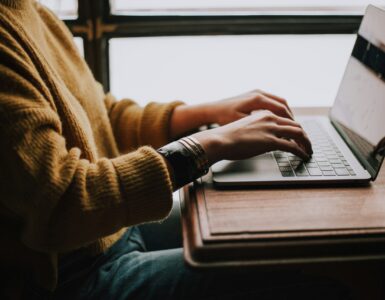 A student typing on a laptop while drafting a clear email to a teacher.