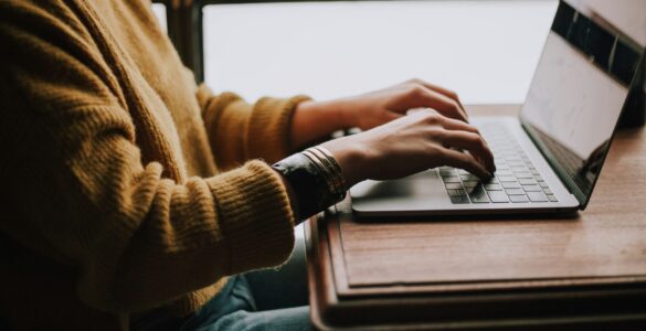 A student typing on a laptop while drafting a clear email to a teacher.