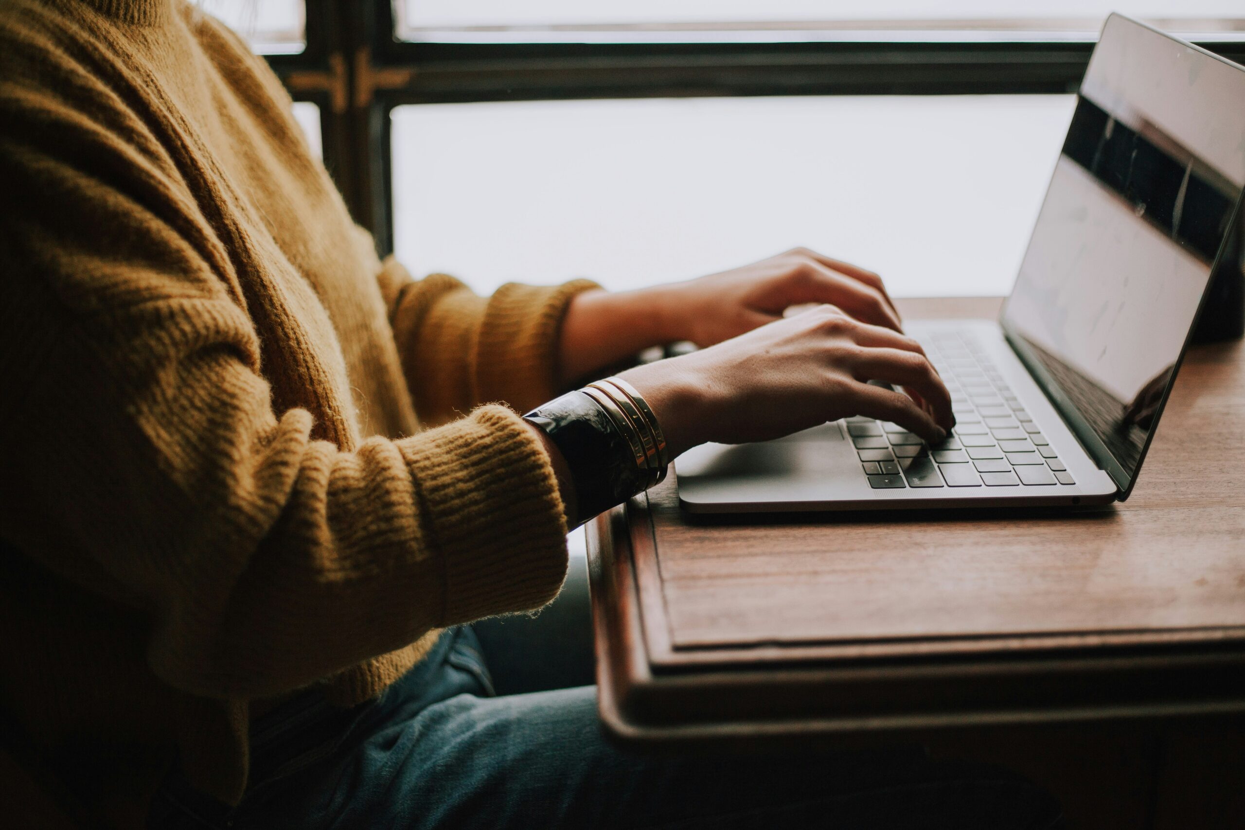 A student typing on a laptop while drafting an email, representing messages that can include remote content.