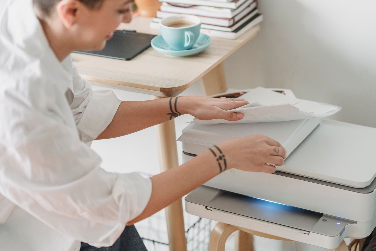 A person places white paper into a printer, illustrating how standard paper sizes simplify printing and scaling.