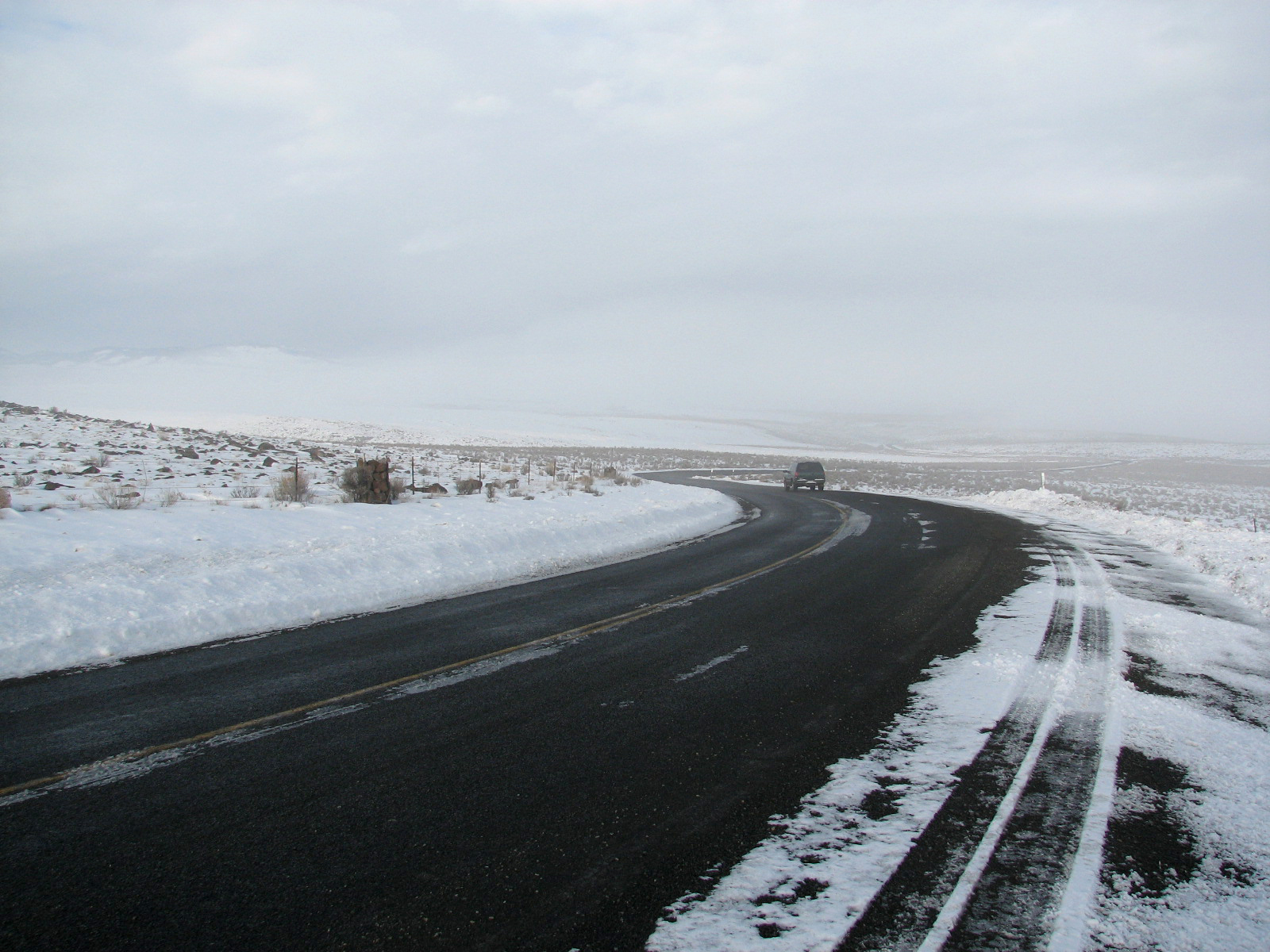 A thin, glossy layer of black ice covers part of a winter road.
