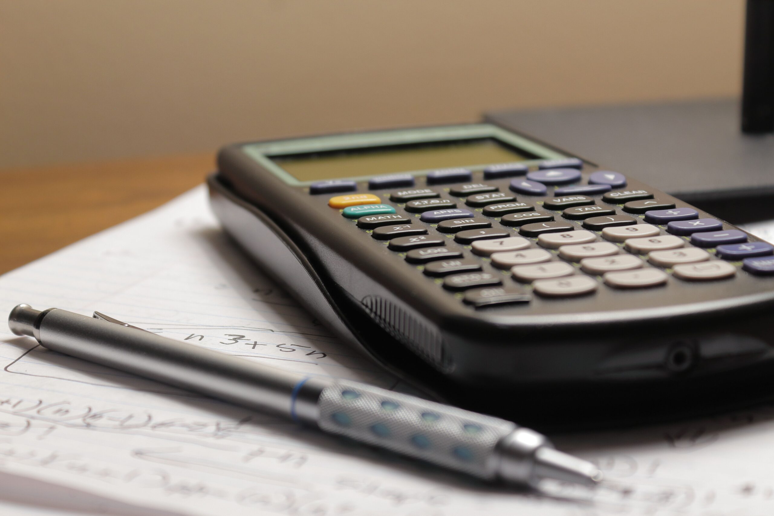 A calculator and handwritten calculus notes used to organize an optimization problem step by step.