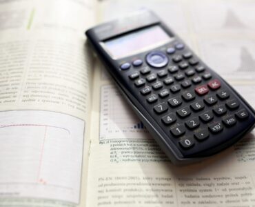A scientific calculator on an open calculus textbook for working through optimization problems.