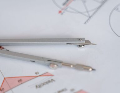 A compass and ruler on a circular geometry diagram used to study radius and area.