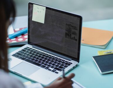 A student reviews application notes beside a laptop.