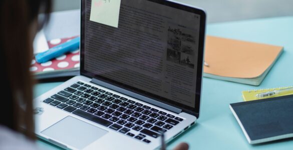 A student reviews application notes beside a laptop.