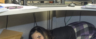 Workers shelter under desks while practicing Drop, Cover, and Hold On during an earthquake drill