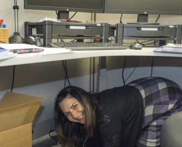Workers shelter under desks while practicing Drop, Cover, and Hold On during an earthquake drill