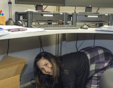 Workers shelter under desks while practicing Drop, Cover, and Hold On during an earthquake drill