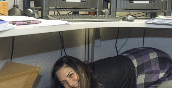 Workers shelter under desks while practicing Drop, Cover, and Hold On during an earthquake drill