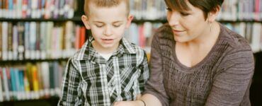 A student and adult discuss a book together during supported reading.
