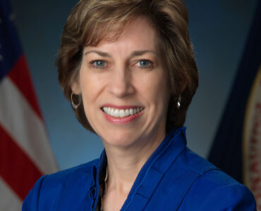 Ellen Ochoa in an official NASA portrait, wearing a blue jacket.