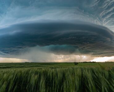 A large supercell thunderstorm over green prairie fields