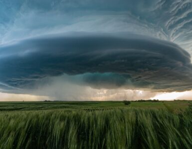 A large supercell thunderstorm over green prairie fields