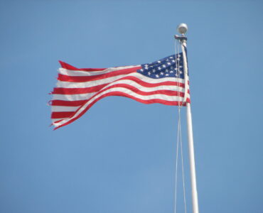 An American flag waving above the U.S. Capitol, representing federal budget decisions made by Congress.