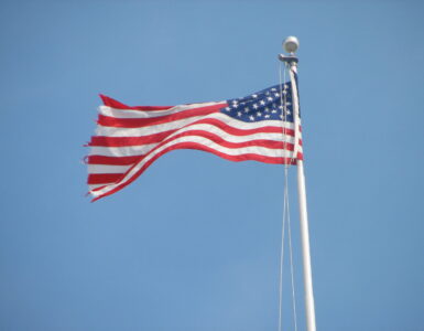 An American flag waving above the U.S. Capitol, representing federal budget decisions made by Congress.