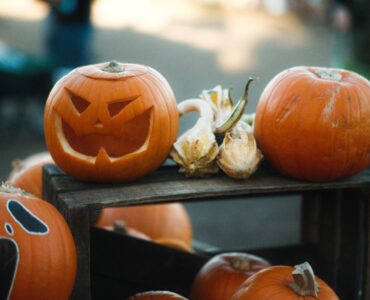 Carved jack-o'-lanterns displayed with uncarved pumpkins on wooden crates.