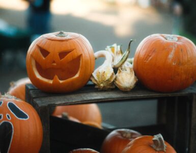 Carved jack-o'-lanterns displayed with uncarved pumpkins on wooden crates.