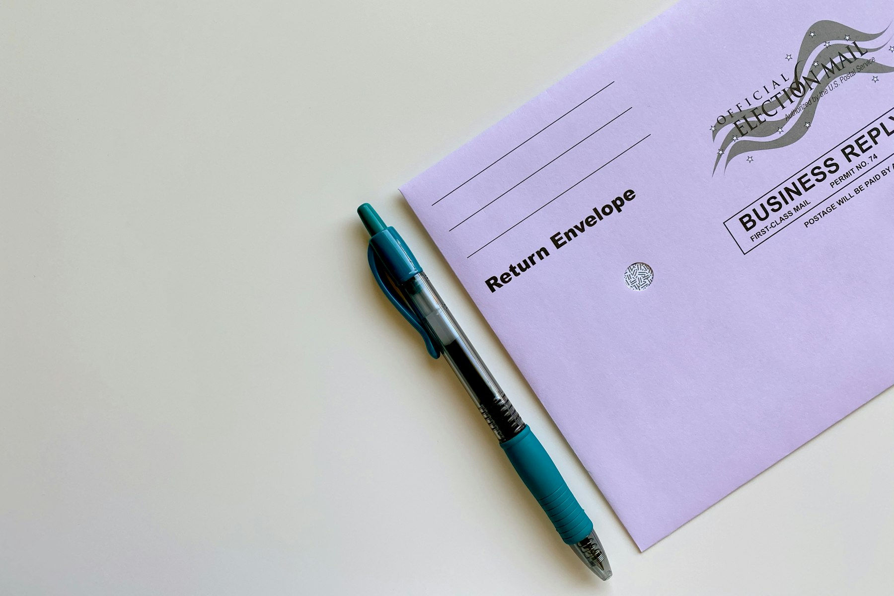 A pen resting on an American election mail ballot envelope