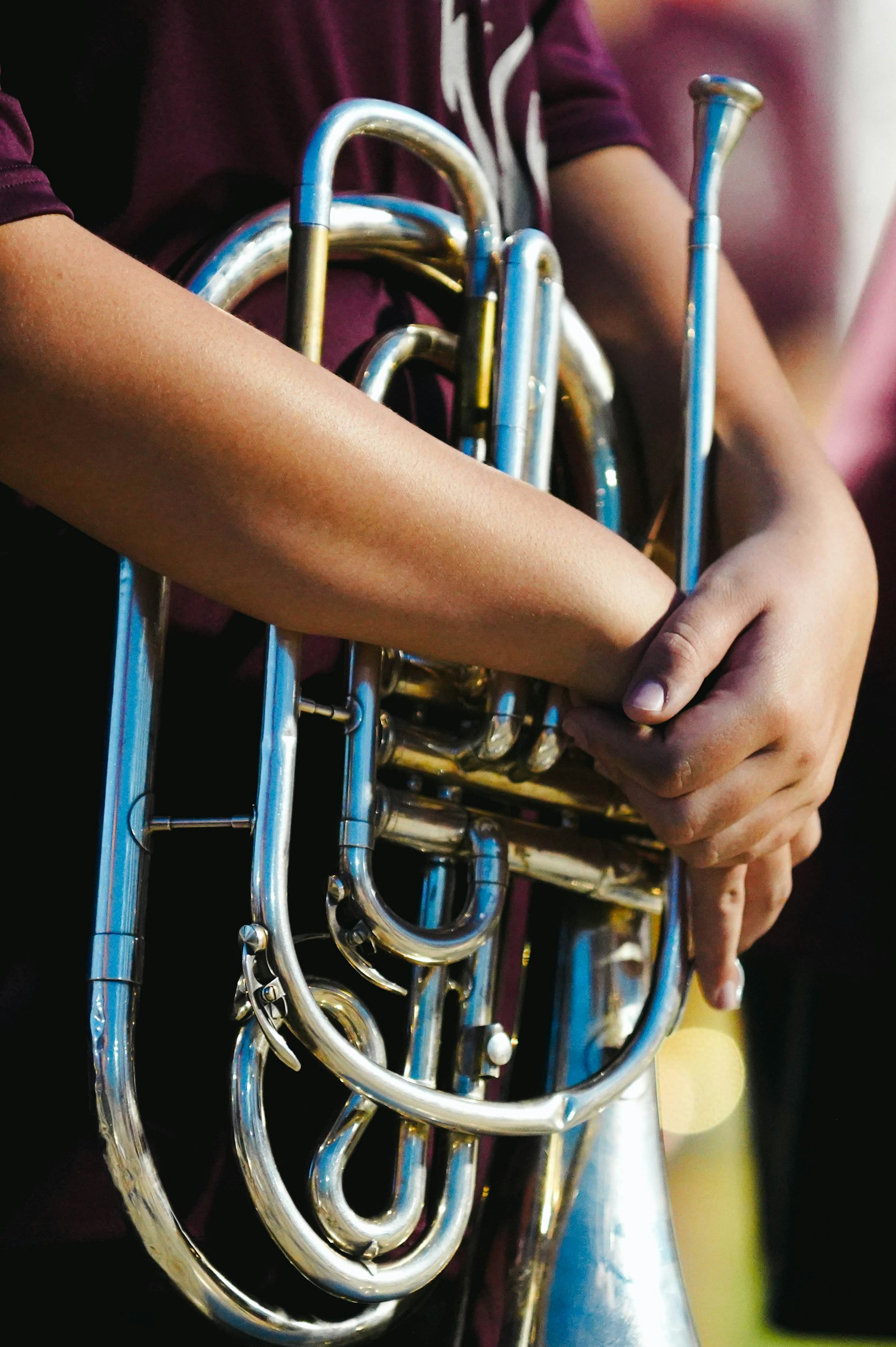 A marching musician holds a polished mellophone in playing position.