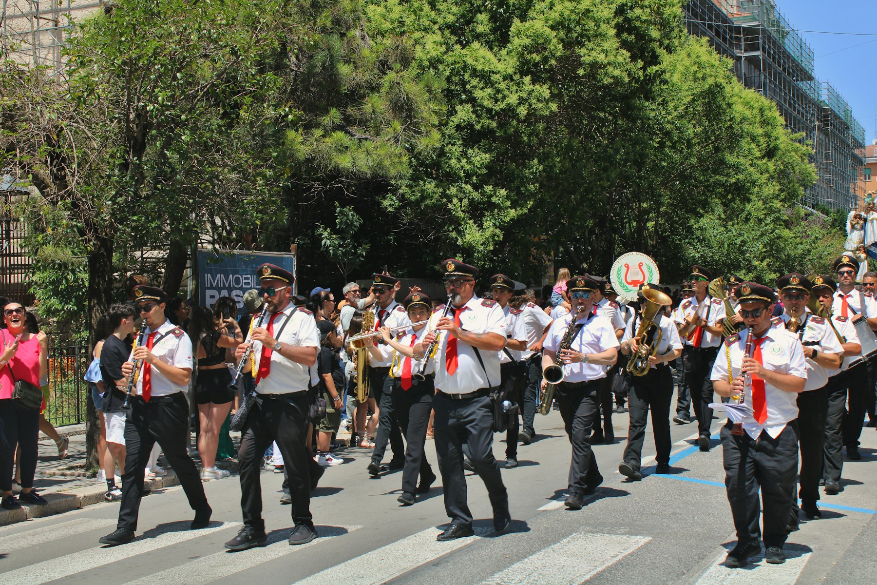 Marching band musicians play brass and woodwind instruments while moving through a parade.